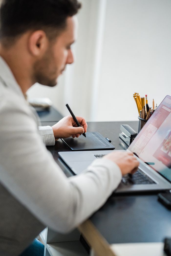 Professional man using a laptop and stylus for design in a modern office setting.